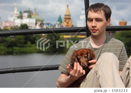 young man holds dachshund on hands outdoor in summer young man holds dachshund on hands outdoor in summer 3563233
