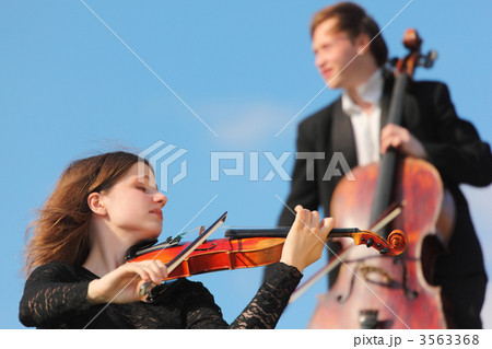 violinist and violoncellist play against sky 3563368