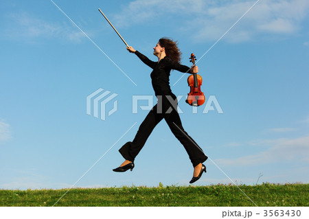 girl with violin jumps on grass against  sky 3563430