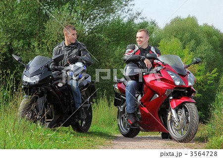 two motorcyclists standing on country road, without helmets 3564728