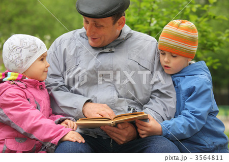 grandfather with grandchildren reads book outdoor 3564811