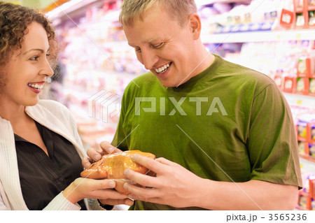 Smiling young man and woman buy chicken in supermarket Smiling young man and woman buy chicken in supermarket 3565236