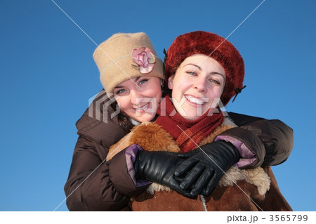 young woman embraces other against blue sky in winter 3565799