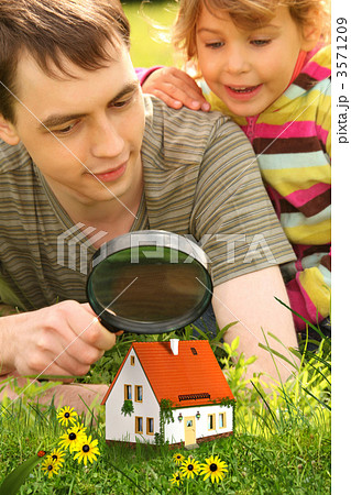 father with little girl looking on small house through magnifier father with little girl looking on small house through magnifier 3571209