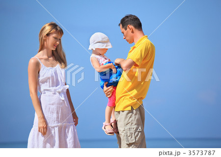 Happy family with little girl in white hat against sea Happy family with little girl in white hat against sea 3573787