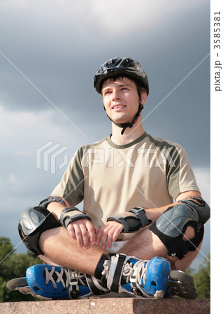 Boy on rollerblades sits with crossed legs 3585381