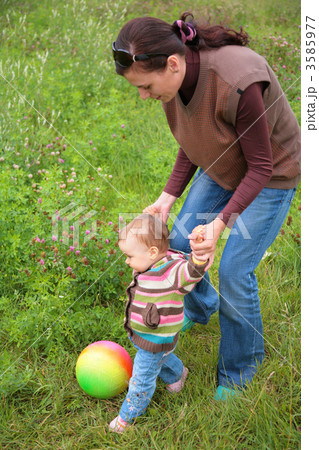 Mother and baby play with ball on grass 3585977