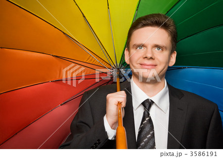 smiling businessman in suit with multi-coloured umbrella 3586191