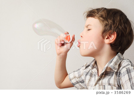 little caucasian boy blowing soap bubbles on white background, s 3586269