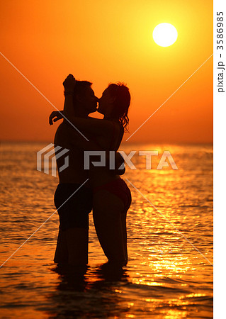 Couple ebraces and kisses in sea on sunset 3586985