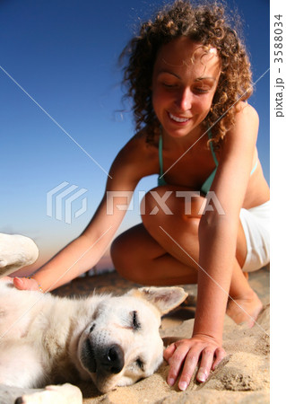 Girl with dog sits on sand 3588034