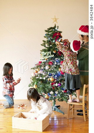 クリスマスツリーの飾り付けをする子供たちと母親の写真素材