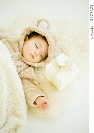 着ぐるみで寝る赤ちゃんと枕元のプレゼント 3677625