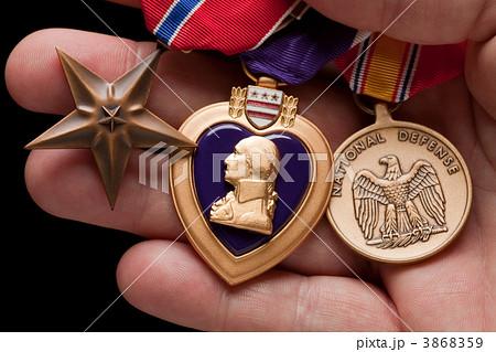 Man Holding Purple Heart, Bronze and National Defense War Medals Man Holding Purple Heart, Bronze and National Defense War Medals 3868359