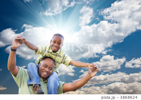 Happy African American Man with Child Over Clouds and Sky Happy African American Man with Child Over Clouds and Sky 3868624