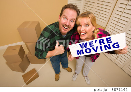Goofy Couple Holding We're Moving Sign Surrounded by Boxes Goofy Couple Holding We're Moving Sign Surrounded by Boxes 3871142