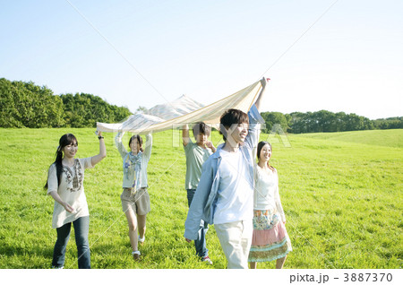 布を持ち草原を歩く若者たち 3887370