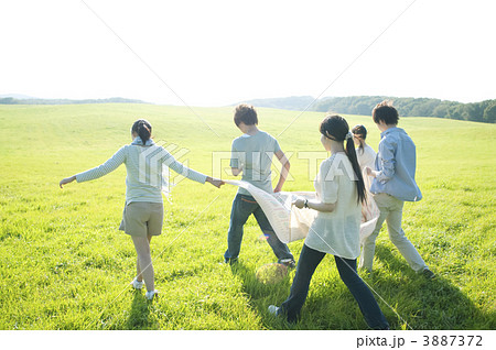 布を持ち草原を歩く若者たち 3887372