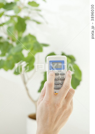 エアコンのリモコンを持つ手 3896030