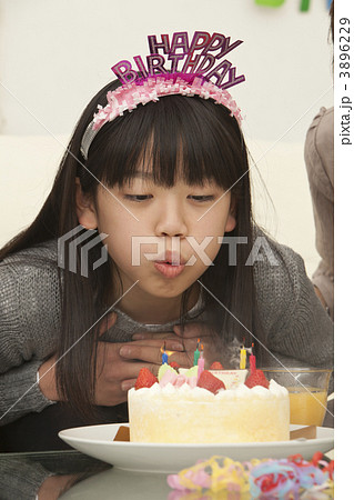 バースデーケーキのろうそくを吹き消す女の子の写真素材