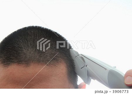 バリカンで髪を頭を丸める男性の写真素材
