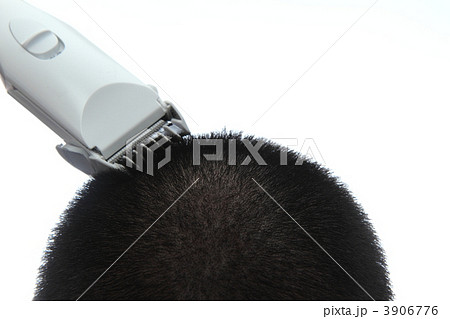 バリカンで髪を頭を丸める男性の写真素材