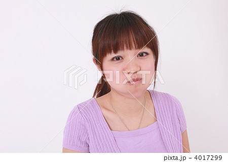 ほっぺを膨らませる紫色の洋服を着た女性の写真素材