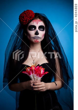 Serious woman in skull face art mask and flowers 4044869