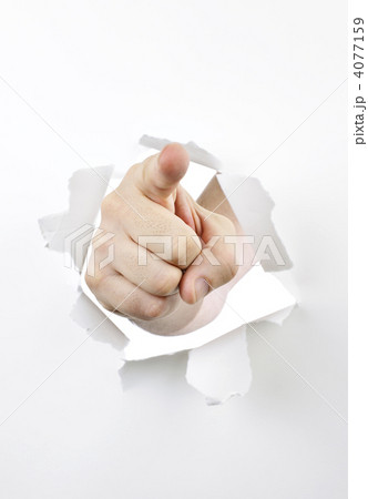 Finger pointing through hole in paper 4077159