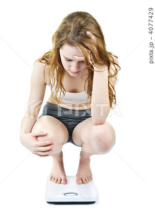 Young girl on bathroom scale looking upset 4077429