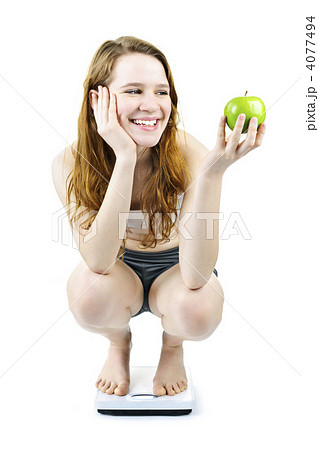 Young smiling girl on bathroom scale holding apple 4077494