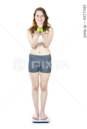 Young smiling girl on bathroom scale holding apple Young smiling girl on bathroom scale holding apple 4077495