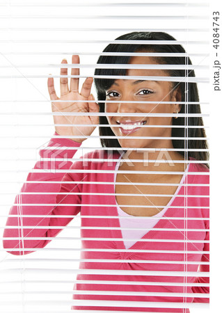 Smiling woman looking through blinds 4084743