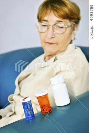 Elderly woman looking at pill bottles 4093769