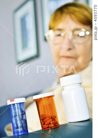Elderly woman looking at pill bottles 4093770