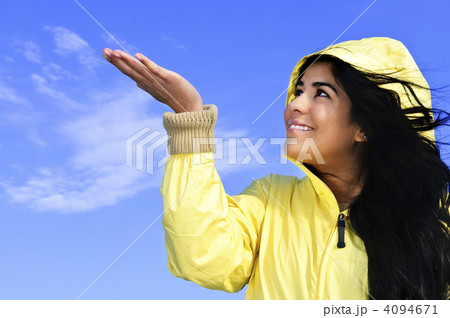 Beautiful young woman in raincoat checking for rain Beautiful young woman in raincoat checking for rain 4094671