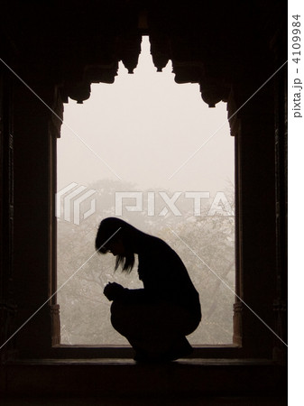 祈りを捧げる女性のシルエットの写真素材