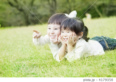 芝生で頬杖をつく子供達の写真素材