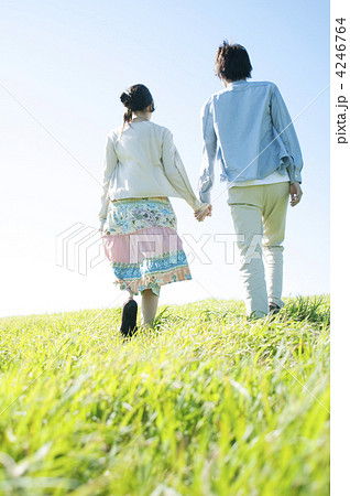 草原を歩くカップルの後姿の写真素材