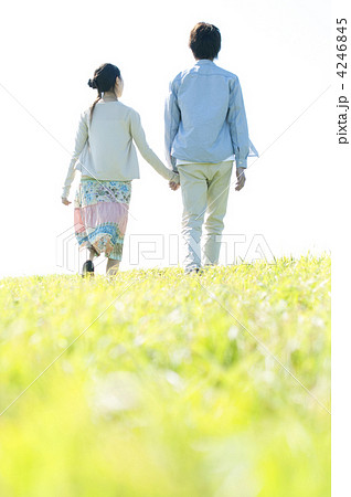 草原を歩くカップルの後姿の写真素材