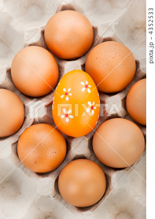 Easter background. Eggs in cardboard container and one painted e Easter background. Eggs in cardboard container and one painted e 4352533
