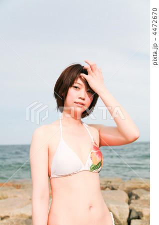 髪をかき上げる しぐさ 横目 真夏の海岸浜辺 若い水着の女性の写真素材