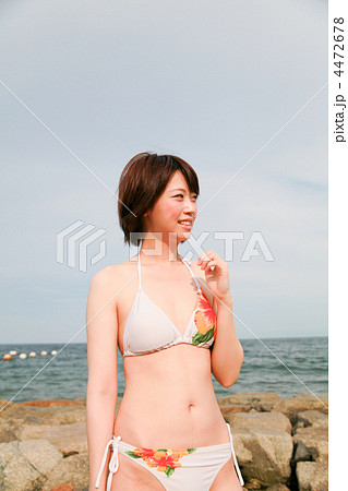 笑顔 振り向く 横顔 真夏の海岸浜辺 若い水着の女性の写真素材