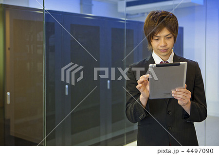 サーバールームの前でタブレット端末を操作するビジネスマン 4497090
