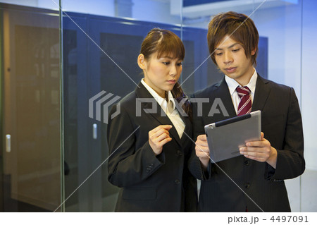 サーバールームの前でタブレット端末を見ながら話をする男女ビジネスマン サーバールームの前でタブレット端末を見ながら話をする男女ビジネスマン 4497091