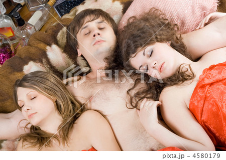 Sleeping young man and two women after a party 4580179