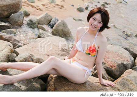 笑顔 カメラ目線 色白 夏休み 海岸 ビーチ 岩場 若い女性の写真素材