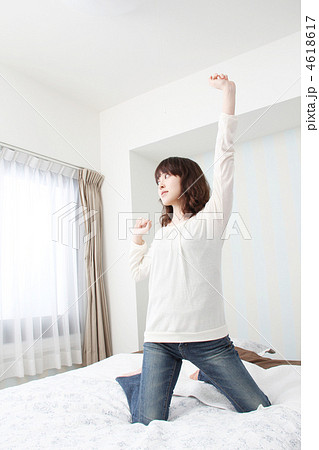 ベッドの上で膝立ちをして背伸びをしている女性 ベッドの上で膝立ちをして背伸びをしている女性 4618617