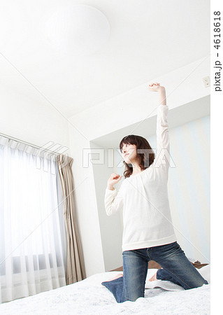 ベッドの上で膝立ちをして背伸びをしている女性 4618618