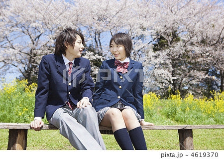 ベンチに座り話をする高校生カップルの写真素材